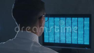 戴眼镜的专业IT极客程序员在夜间办公室用二进制代码工作